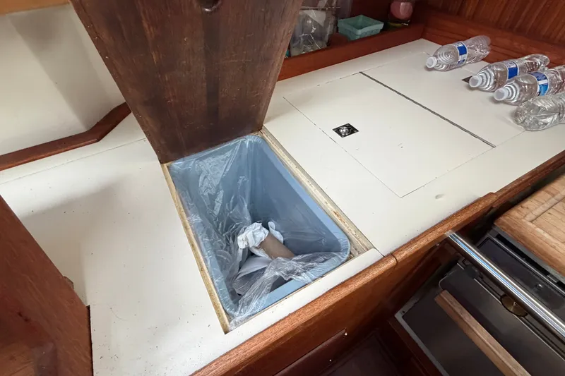 Slide: The Image of Interior of 1990 Sabre 34 MK II sailboat showing kitchen waste bin and water bottles. - 36