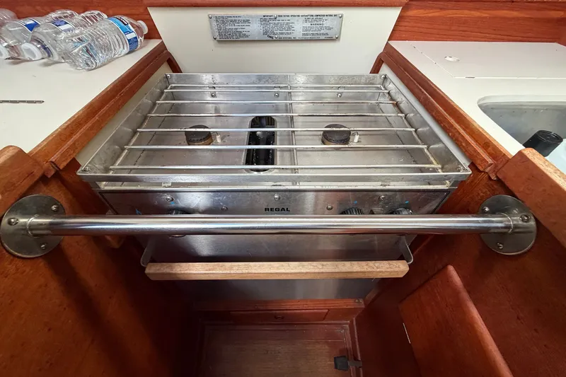 Slide: The Image of Stove in 1990 Sabre 34 MK II yacht galley with wooden cabinetry and water bottles. - 35