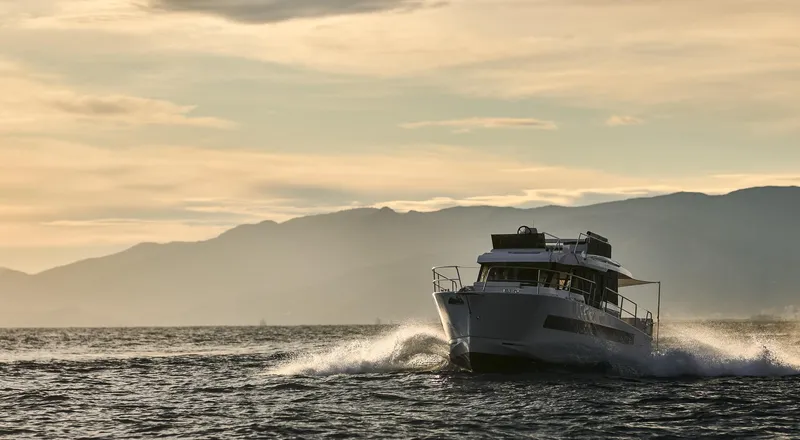 Slide: The Image of 2025 Northman 1300 yacht cruising at sunset with mountains in the background. - 7
