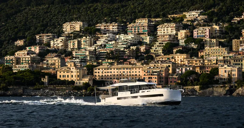 Slide: The Image of 2025 Northman 1300 yacht cruising near a scenic coastal town. - 5