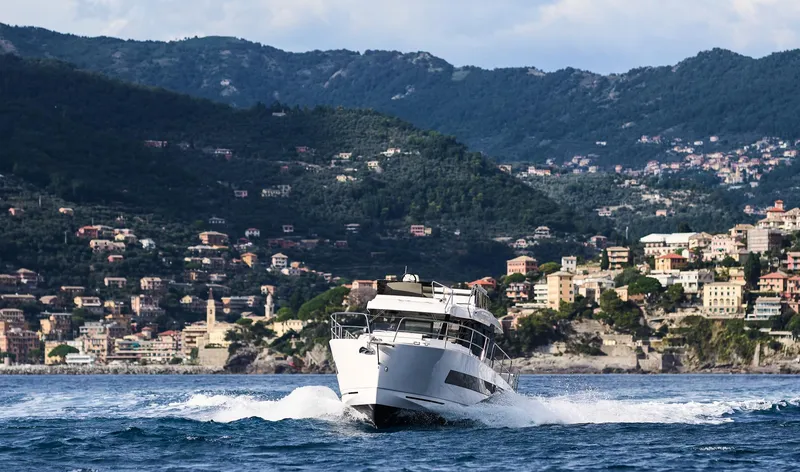 Slide: The Image of 2025 Northman 1300 yacht cruising near scenic coastal town with mountainous backdrop. - 27