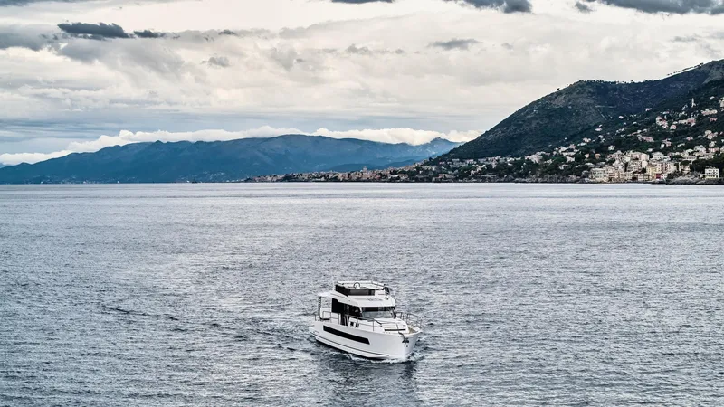 Slide: The Image of 2025 Northman 1300 yacht cruising on a scenic coastal waterway with mountainous backdrop. - 11
