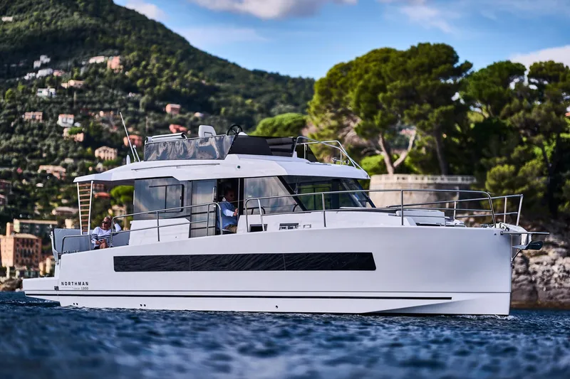 Slide: The Image of 2025 Northman 1300 yacht cruising near scenic coastline with lush greenery. - 24