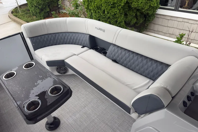 Slide: The Image of 2023 Harris Sunliner 230 boat interior with cushioned seating and table with cup holders. - 6