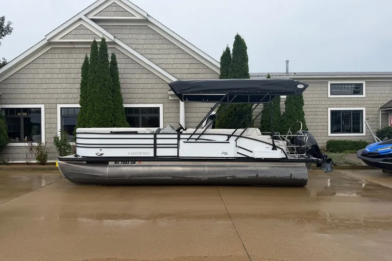 The Image of 2023 Harris Sunliner 230 pontoon boat parked outside a building on a wet driveway. - 0
