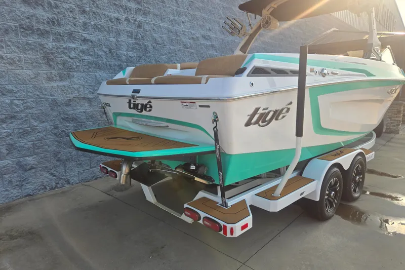 The Image of 2020 Tigé 23ZX boat with teal accents on a trailer, parked by a stone wall. - 2