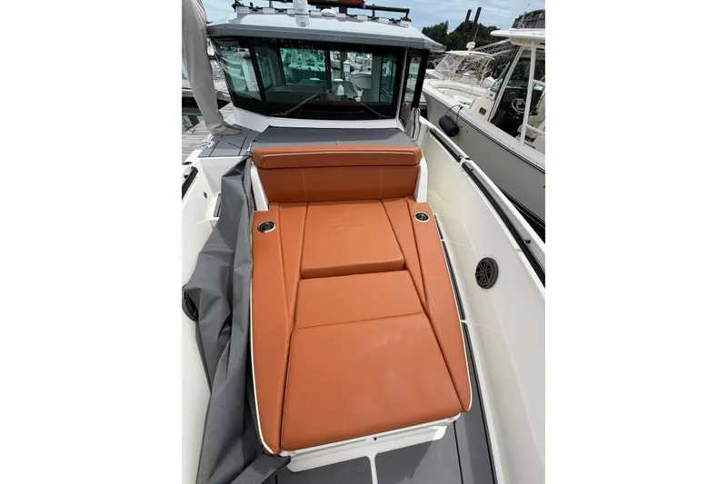 Slide: The Image of 2025 Saxdor 320 GTC boat with orange sunbed and sleek design at a marina. - 13
