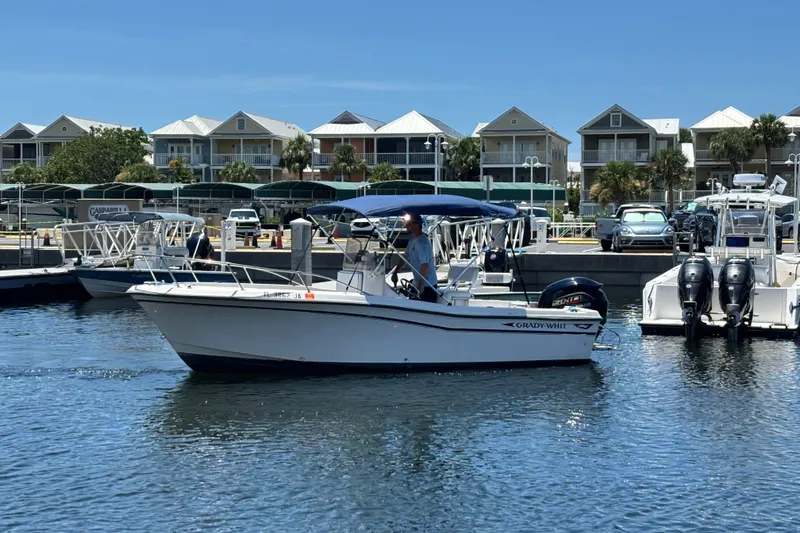 Slide: The Image of 1994 Grady-White Escape 209 boat docked in marina, with waterfront homes in background. - 2