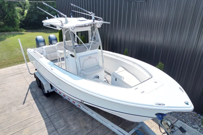 Slide: The Image of 2008 Sea Hunt Triton 260 boat on trailer, white exterior, dual engines, parked outdoors. - 15