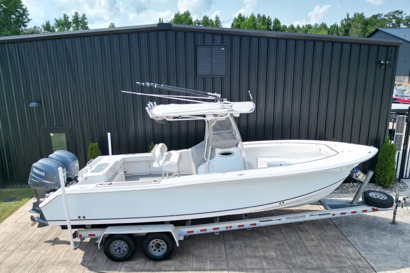 Slide: The Image of 2008 Sea Hunt Triton 260 boat on trailer, parked near a black building. - 30