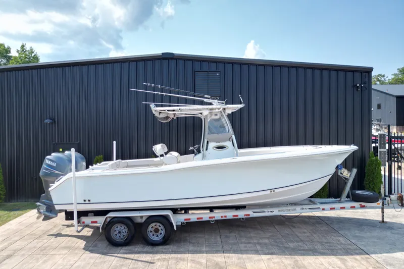 The Image of 2008 Sea Hunt Triton 260 boat on trailer, parked outside a black building. - 1