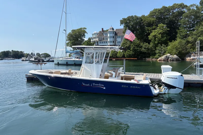 Slide: The Image of 2024 Sea Born LX24 Center Console boat docked with American flag and Honda engine. - 3