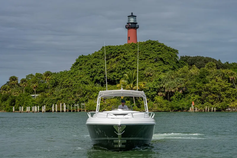 Slide: The Image of A 2009 Intrepid 370 boat cruising in front of a lighthouse and lush greenery. - 2