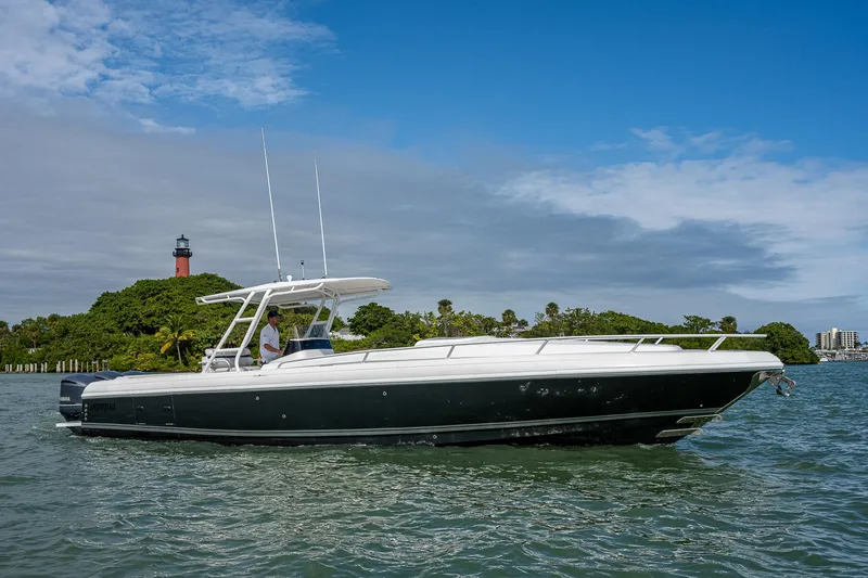 The Image of A 2009 Intrepid 370 boat on calm water near a green island with a lighthouse. - 0