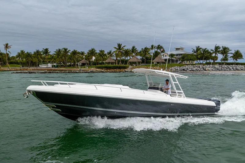 Slide: The Image of A 2009 Intrepid 370 boat cruising on the water, surrounded by palm trees and a cloudy sky. - 3