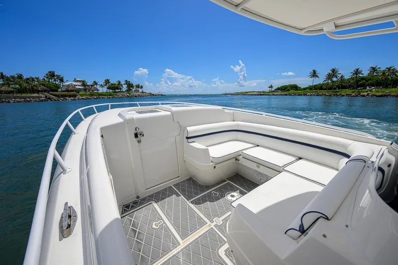 Slide: The Image of 2009 Intrepid 370 boat interior with white seating, cruising on a sunny day near palm-lined shore. - 7