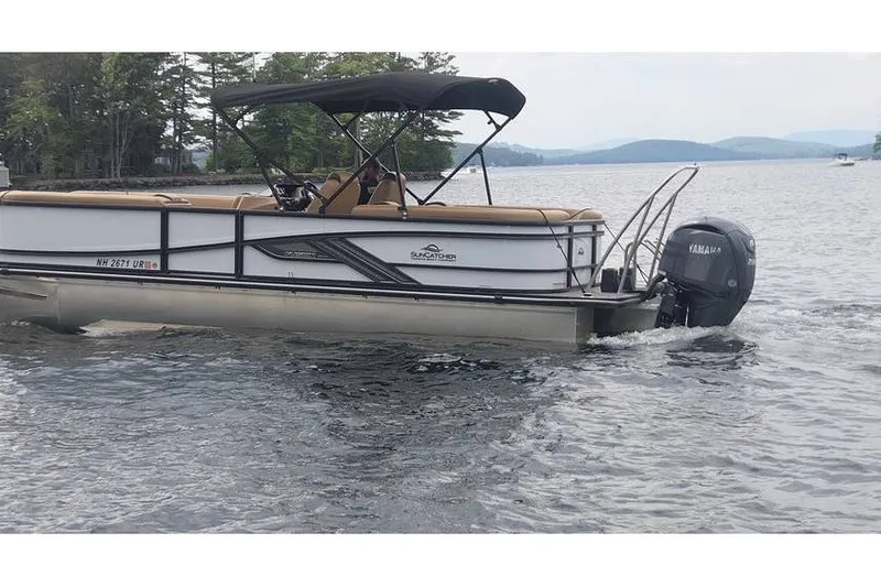 Slide: The Image of 2025 SunCatcher 324 Rc Fusion pontoon boat cruising on a scenic lake. - 2