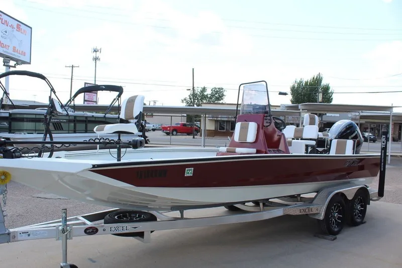 Slide: The Image of 2025 Excel 220 Bay Pro Elite boat on trailer, red and white design, parked outdoors. - 10