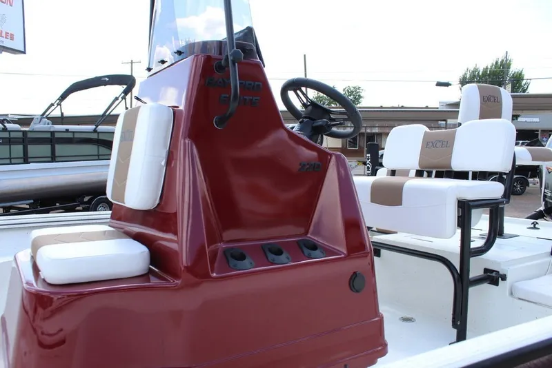 Slide: The Image of 2025 Excel 220 Bay Pro Elite boat interior with red console and white seating. - 11