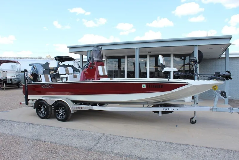 The Image of 2025 Excel 220 Bay Pro Elite boat on trailer, red and white design, parked outdoors. - 1