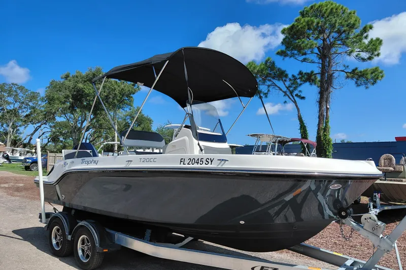 The Image of 2020 Bayliner Trophy T20CC boat on trailer, parked outdoors under clear blue sky. - 1
