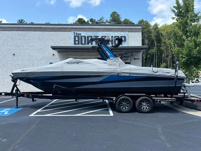 Slide: The Image of A 2023 Centurion Fi25 boat on a trailer, covered, parked in front of a shop. - 7