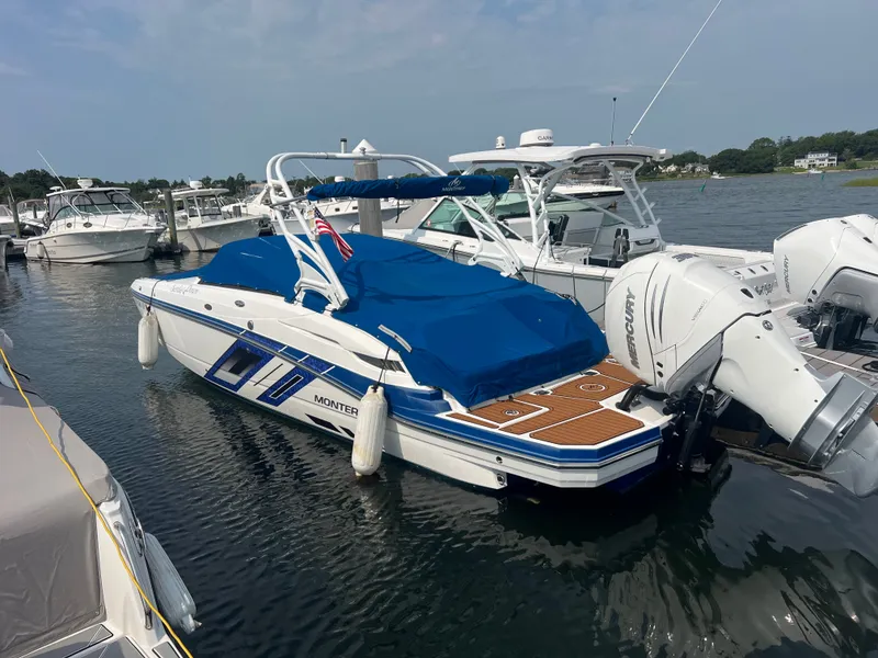 The Image of A 2019 Monterey M 65 boat is docked in the water. It features blue covers and twin outboard engines. - 1
