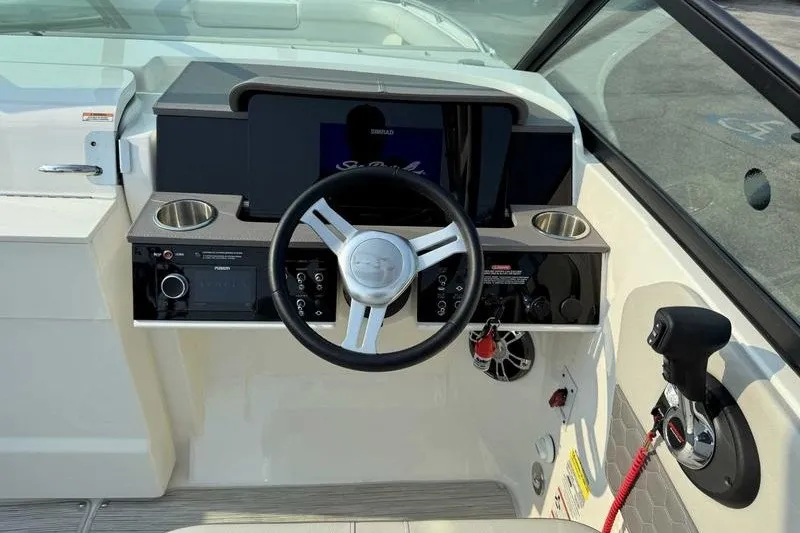 Slide: The Image of 2022 Sea Ray SDX 250 helm with steering wheel, controls, and cup holders. - 17