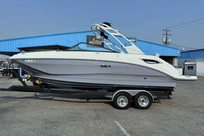 The Image of 2022 Sea Ray SDX 250 boat on trailer, parked outside a blue building. - 0