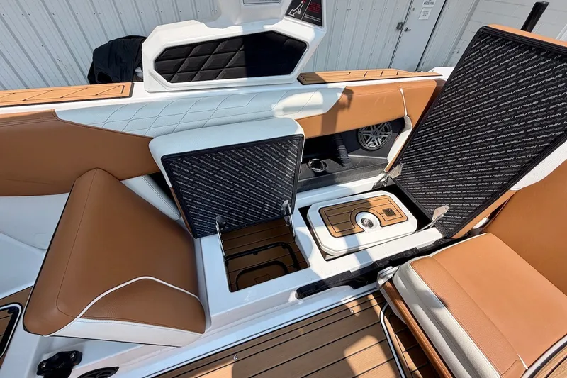 Slide: The Image of 2023 Nautique Super Air Nautique S23 interior with open storage compartments and tan seating. - 25