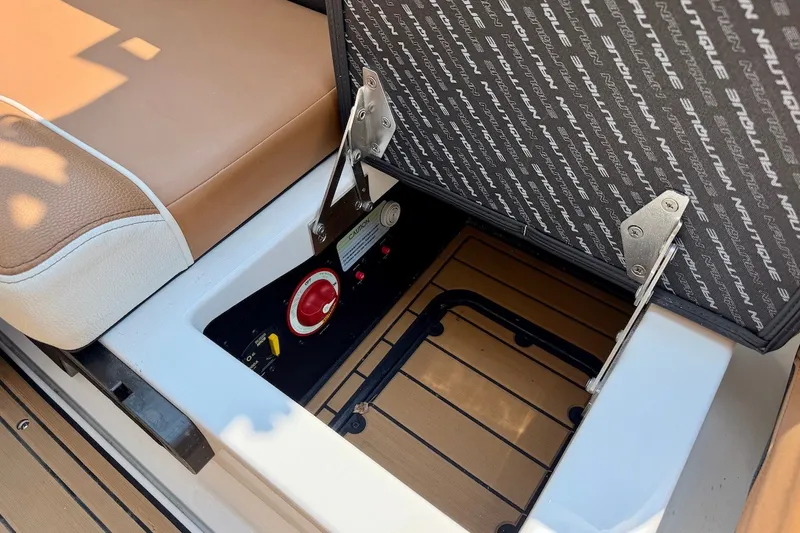 Slide: The Image of 2023 Nautique Super Air Nautique S23 storage compartment with cushioned seating and control panel. - 24