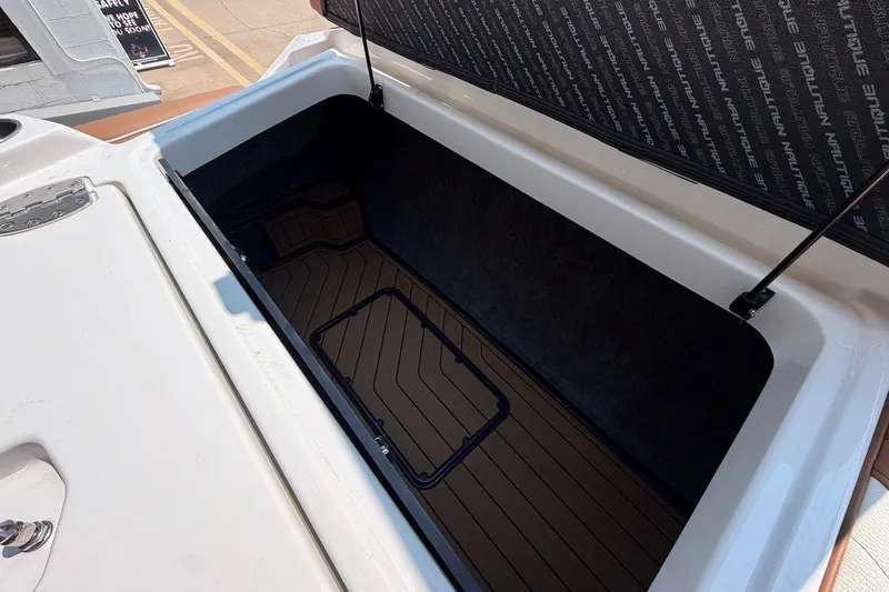 Slide: The Image of 2023 Nautique Super Air Nautique S23 storage compartment, open with visible interior lining. - 27