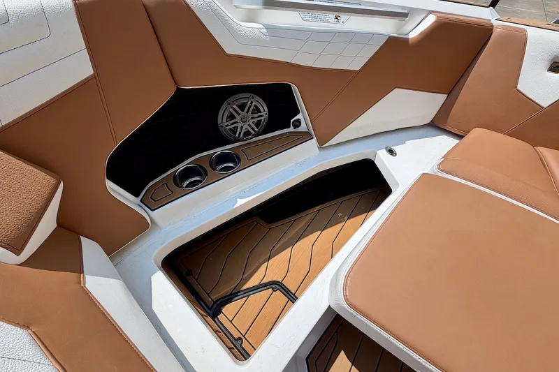 Slide: The Image of 2023 Nautique Super Air Nautique S23 interior with tan seating and storage compartment. - 19