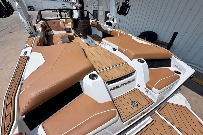 Slide: The Image of 2023 Nautique Super Air Nautique S23 boat interior with tan seating and teak accents. - 11