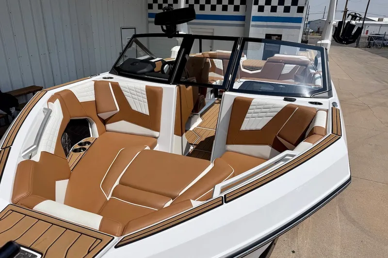 Slide: The Image of 2023 Nautique Super Air Nautique S23 boat interior with tan and white seating. - 2