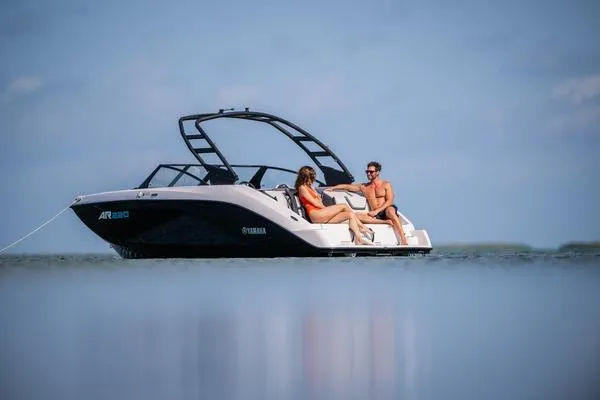 Slide: The Image of 2026 Yamaha Boats AR220 on water with two people relaxing onboard. - 6