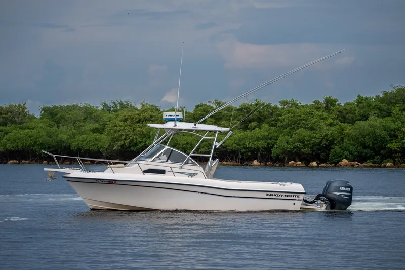 Slide: The Image of 2006 Grady-White Gulfstream 232 boat cruising on calm water near lush greenery. - 14