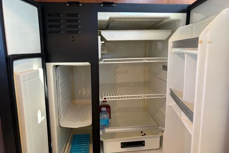 Slide: The Image of Open refrigerator inside a 2003 PDQ 34 Power Catamaran, showing shelves and a few items. - 30