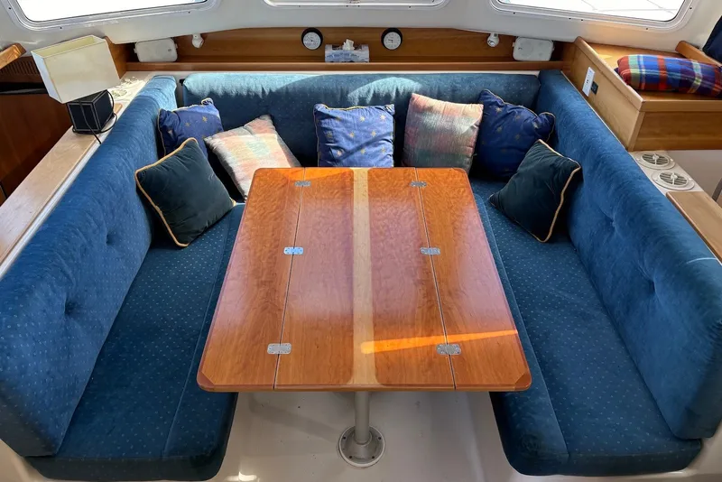 Slide: The Image of Interior of 2003 PDQ 34 Power Catamaran with blue seating and wooden table. - 25