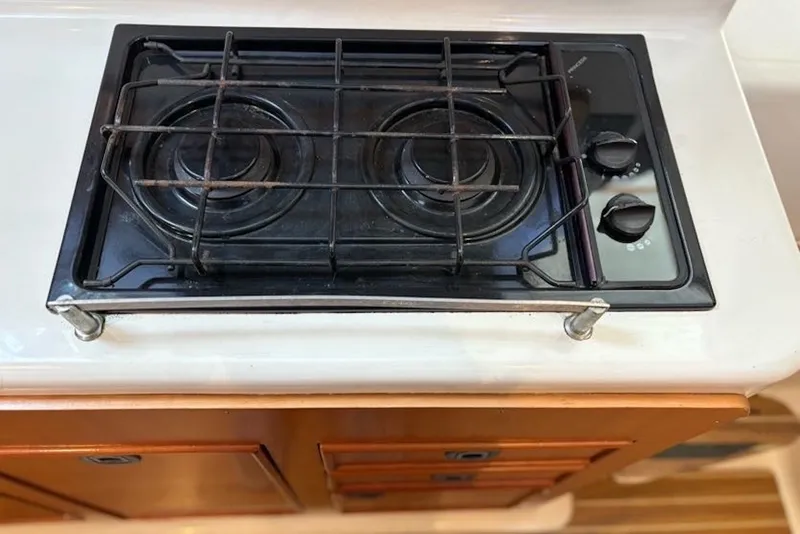 Slide: The Image of Stovetop on 2003 PDQ 34 Power Catamaran, featuring dual burners and control knobs. - 31