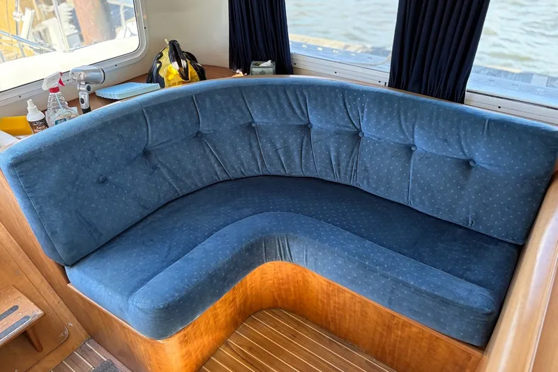 Slide: The Image of Blue cushioned seating inside a 2003 PDQ 34 Power Catamaran, with wooden accents and window view. - 24