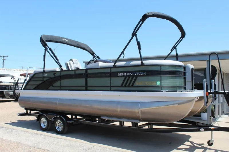 The Image of 2023 Bennington 23 LSR pontoon boat on trailer under clear blue sky. - 1