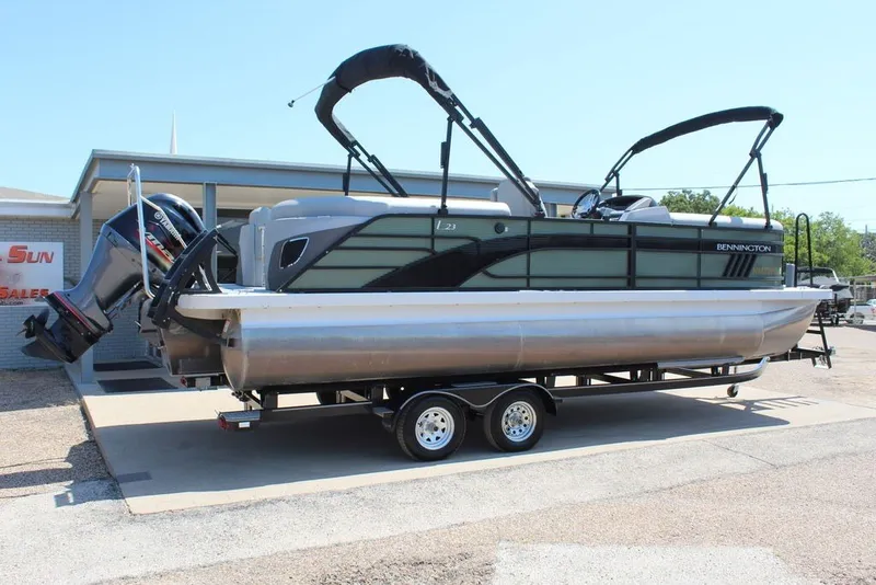 Slide: The Image of 2023 Bennington 23 LSR pontoon boat on trailer, displayed outdoors. - 2