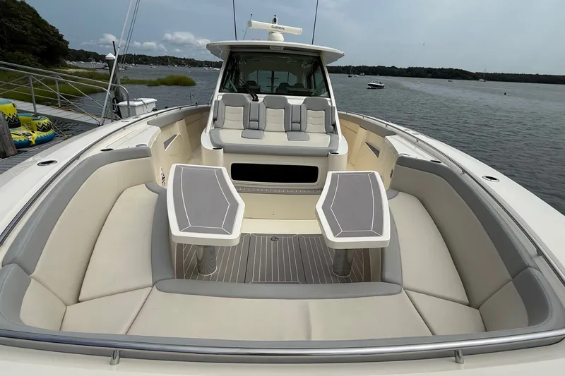 Slide: The Image of 2021 Scout 530 LXF luxury boat interior with seating and tables, docked by a scenic waterfront. - 50