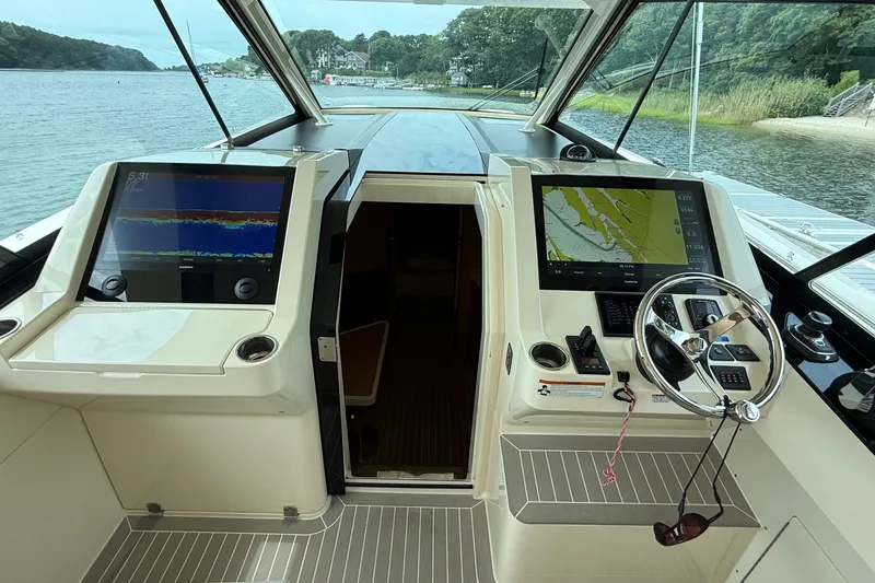 Slide: The Image of 2021 Scout 530 LXF helm with dual navigation screens and steering wheel, docked by a scenic shoreline. - 20