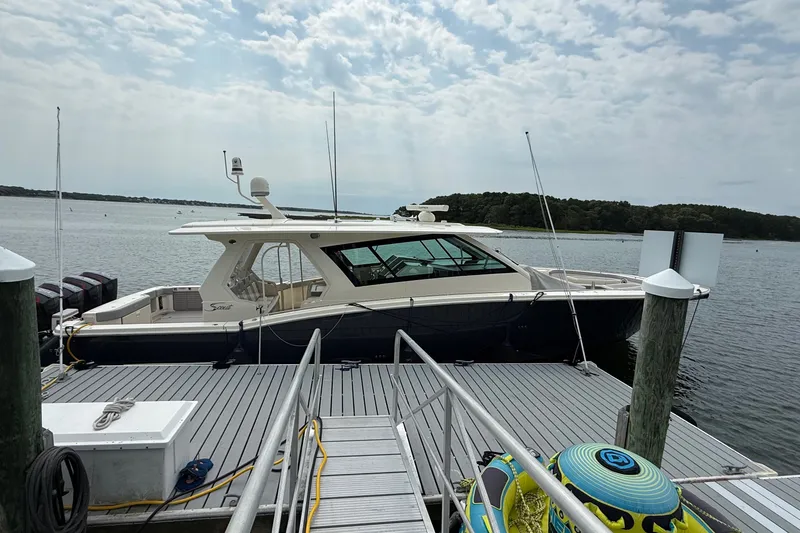 The Image of 2021 Scout 530 LXF luxury yacht docked at a marina under a cloudy sky. - 0