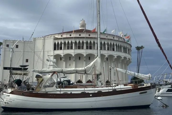 Slide: The Image of 1979 Hans Christian 38 Traditional sailboat docked near a historic building with flags. - 59