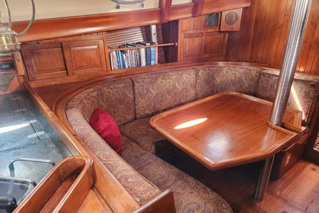 Slide: The Image of 1979 Hans Christian 38 Traditional yacht interior with wooden dining area and cushioned seating. - 19