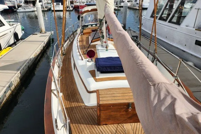 Slide: The Image of 1979 Hans Christian 38 Traditional sailboat docked at marina, showcasing wooden deck and rigging. - 54