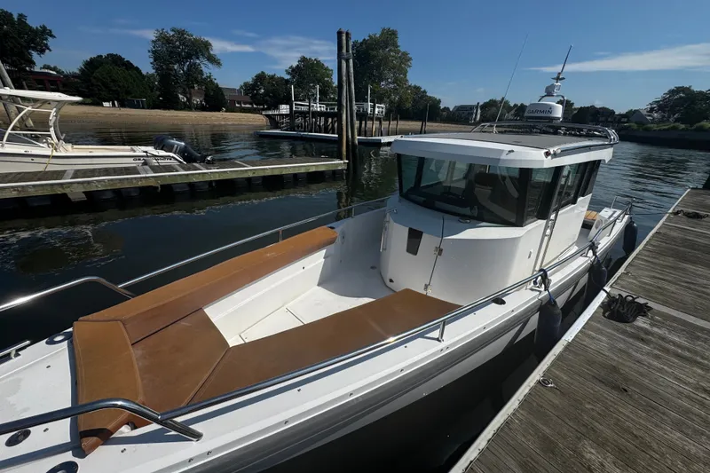 Slide: The Image of 2016 Axopar 28 Cabin boat docked at a marina under a clear blue sky. - 2